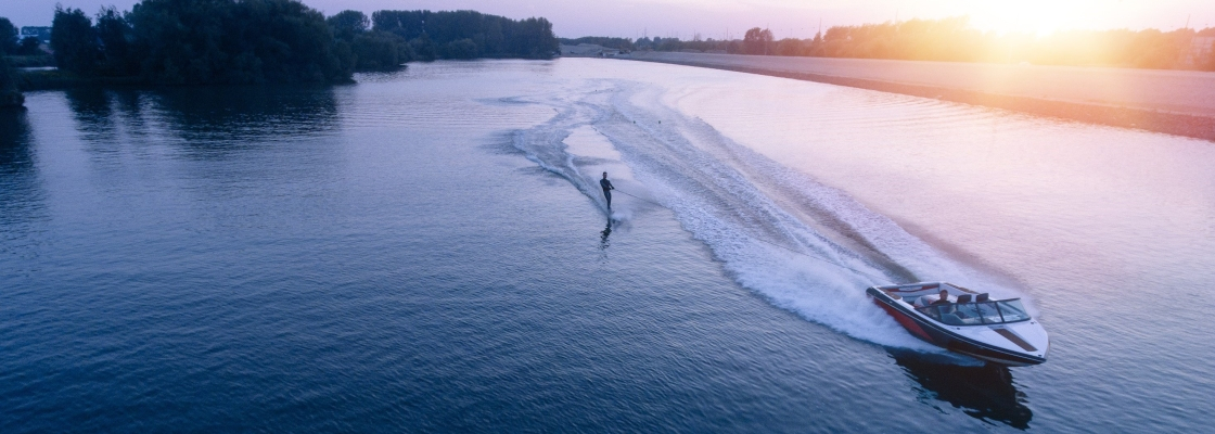 A speedboat driving a person on water-skis around the lake